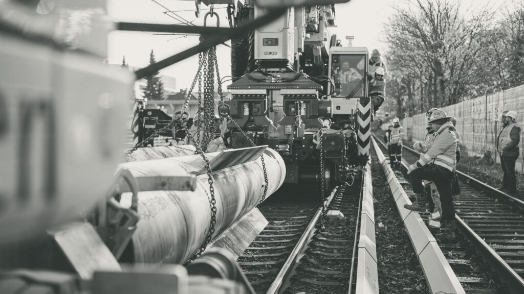 Baukran und Arbeiter auf einer Baustelle mit Gleisen